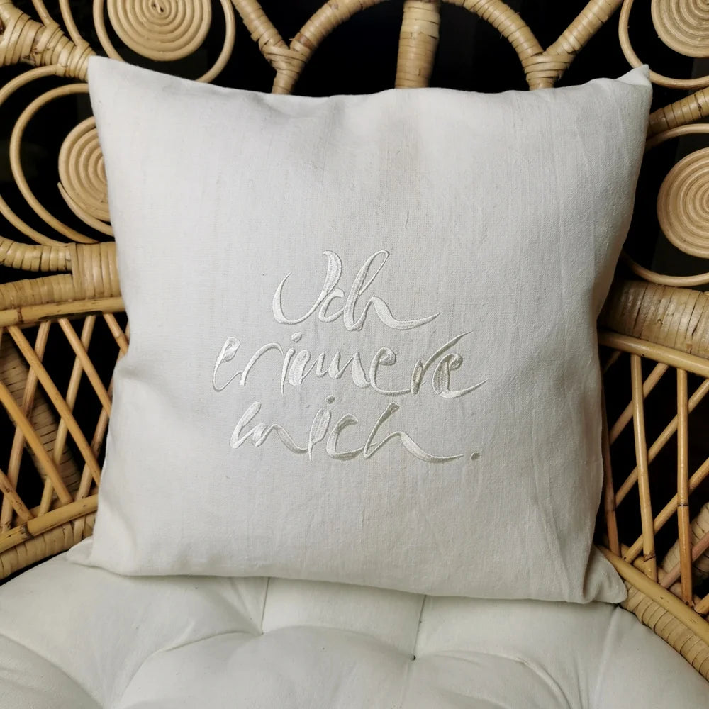 Cremefarbene Kissenhülle „Ich erinnere mich.“ aus handgewebtem Vintage-Bauernleinen, 40x40 cm, dekoriert auf einem Sofa als edles Deko-Unikat