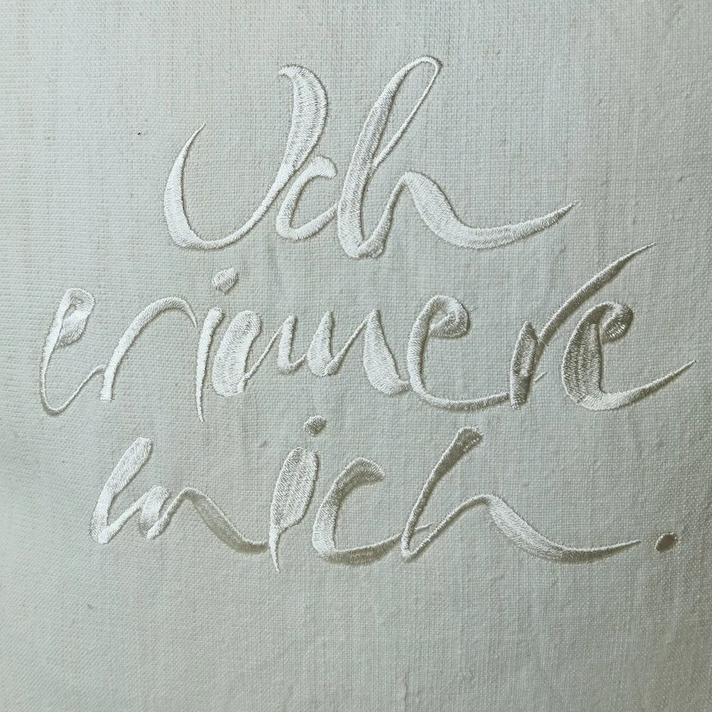 Detailaufnahme der cremefarbenen Stickerei „Ich erinnere mich.“ (Sign by Jwala®) auf naturfarbener Bauernleinen-Kissenhülle mit sichtbarer Struktur