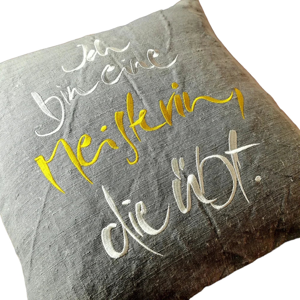 Flach liegende Kissenhülle aus Vintage-Bauernleinen mit silber-goldener Schrift „Ich bin eine Meisterin, die übt.“, sichtbare Leinenstruktur im Nahaufnahme-Fokus