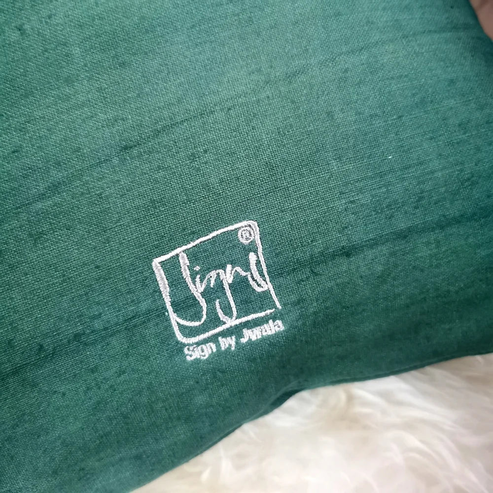 Nahaufnahme der Leinenstruktur der Kissenhülle „Ich vertraue dem Himmel, der mich trägt“ mit sichtbaren Knitterfalten und feiner Stickerei