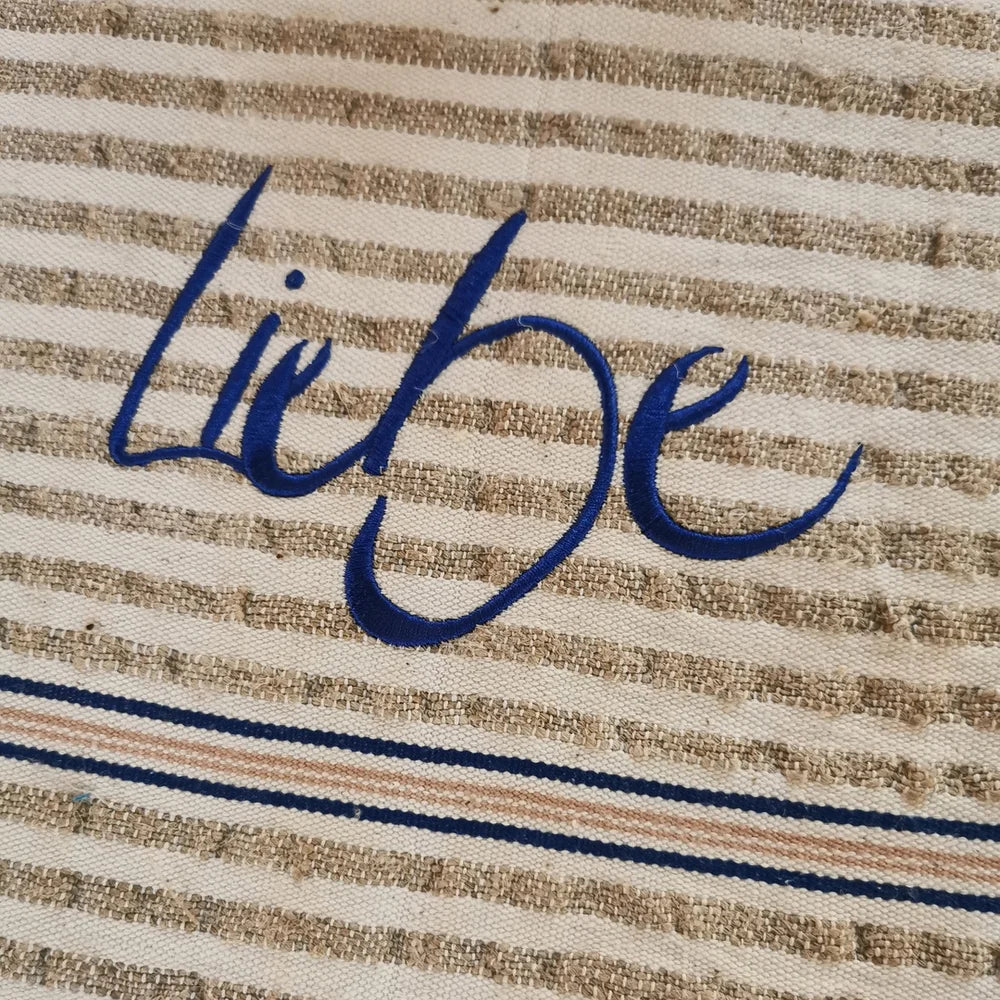 Detailansicht Tischläufer „Liebe“ – blaue Sign-Stickerei auf gestreiftem Bauernleinen