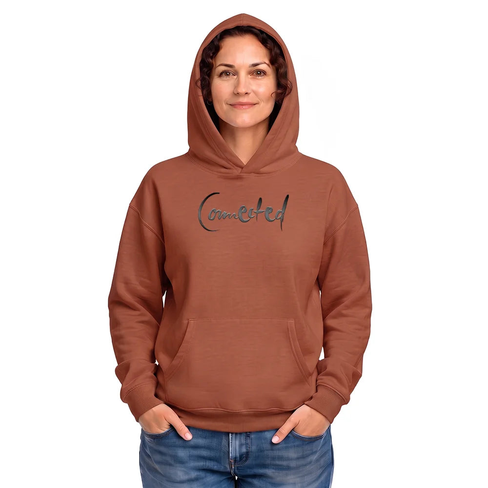 Vorderansicht einer Frau im terracottafarbenen Oversized-Hoodie mit dem feinen, dunklen Sign „Connected“ auf der Brust vor weißem Hintergrund.