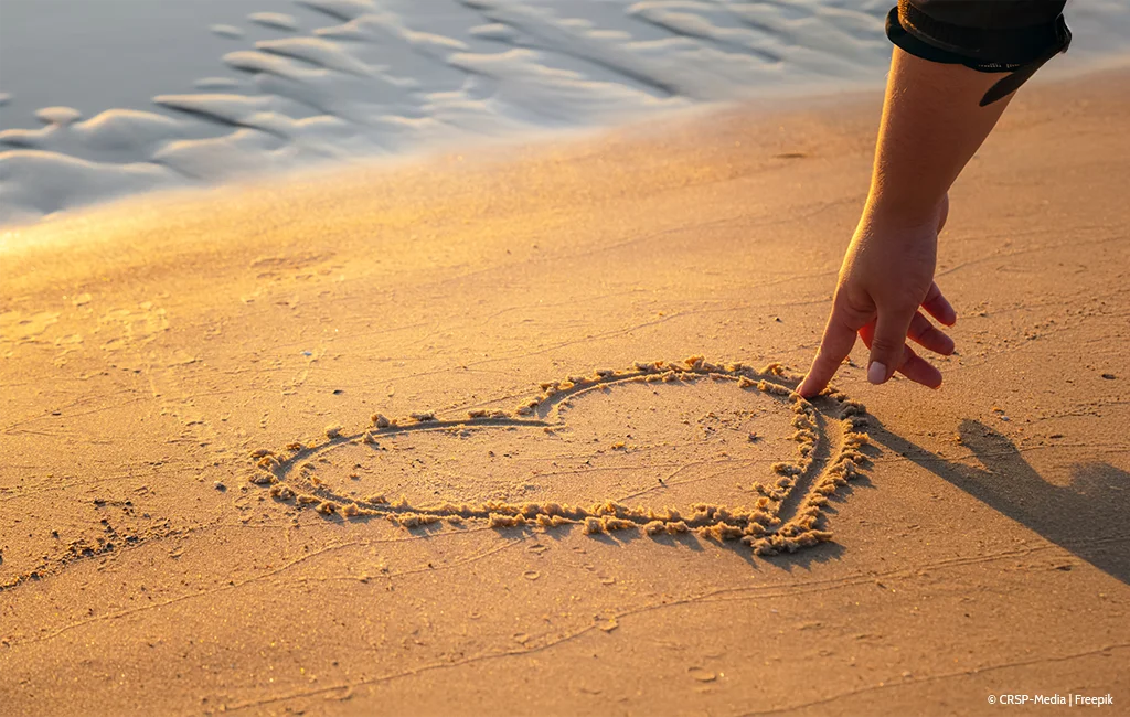 Frau, die ein Herz in den Sand zeichnet – aus dem Onlineshop SignShop Tirol