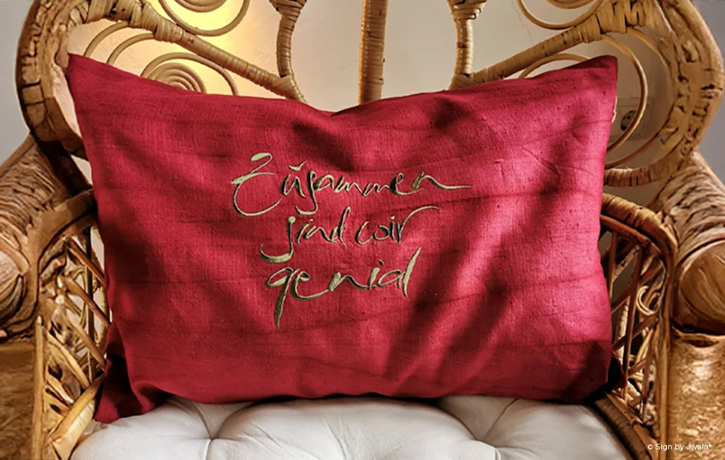 Das Bild zeigt einen Stuhl, auf dem ein Kissen mit liebevollen Sprüchen und inspirierenden Botschaften aus dem SignShop Tirol liegt. Die Kissenhüllen sind farbenfroh wie hier rot, gestaltet und bringen Herzlichkeit sowie positive Energie in den Raum.