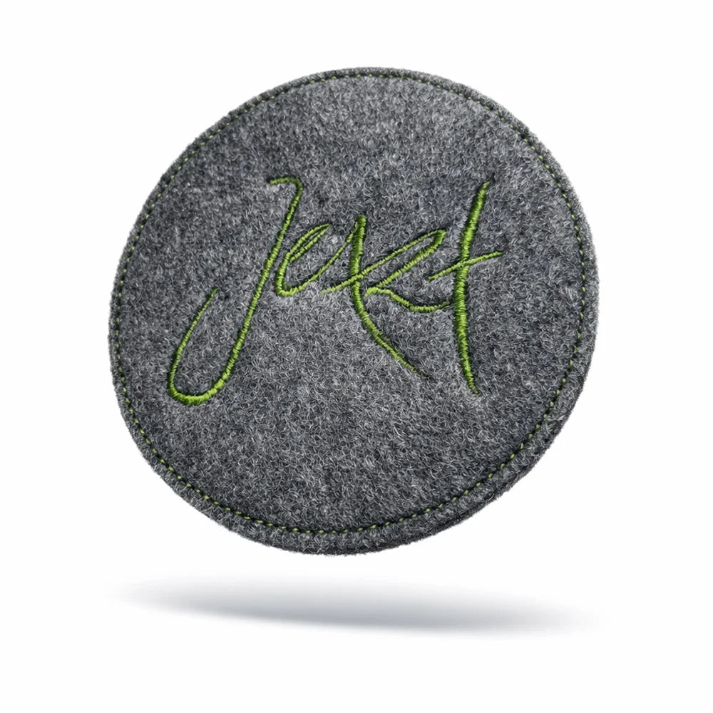 Limitierter Wollwalk-Untersetzer „Jetzt“ in Grau – liebevoll bestickt, ideal für Gläser und Tassen, handgefertigt im SignShop Tirol