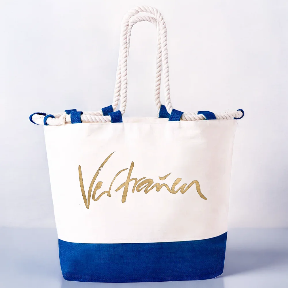 Veredelte Strandtasche aus weißer Baumwolle mit einem kontrastierenden, tiefblauen Juteboden und weißen Kordelgriffen. Die Vorderseite ist mit dem goldenen Wort „Vertrauen“ bedruckt.