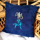 Dunkelblaue Kissenhülle „Alles ist gut“ aus handgewebtem Vintage-Bauernleinen, 40x40 cm, mit hellgrün-türkiser Stickerei auf einem Sofa arrangiert
