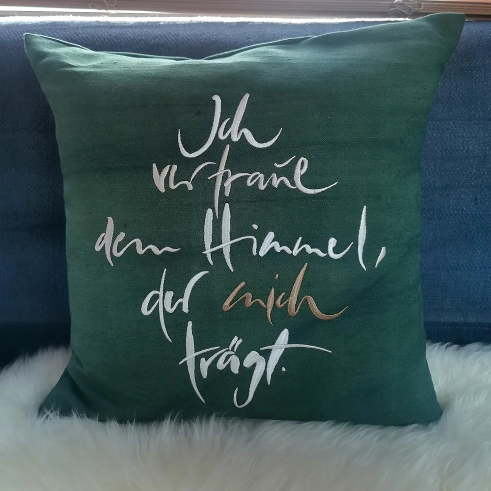 Dunkelgrüne Kissenhülle „Ich vertraue dem Himmel, der mich trägt“ aus handgewebtem Vintage-Bauernleinen, 40x40 cm, dekoriert auf einem Sofa als edles Deko-Unikat