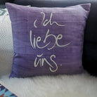 Hellviolette Kissenhülle „Ich liebe uns“ aus handgewebtem Vintage-Bauernleinen, 40x40 cm, dekoriert auf einem Sofa als romantisches Deko-Unikat