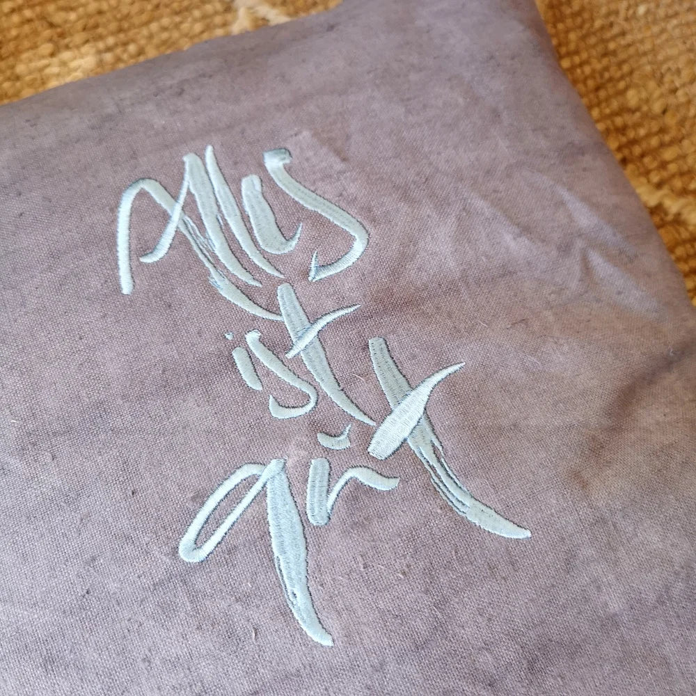 Flach liegende Kissenhülle „Alles ist gut“ in Grau, 40x40 cm, mit Reißverschluss, präsentiert als limitierte, nummerierte Edition aus Tirol