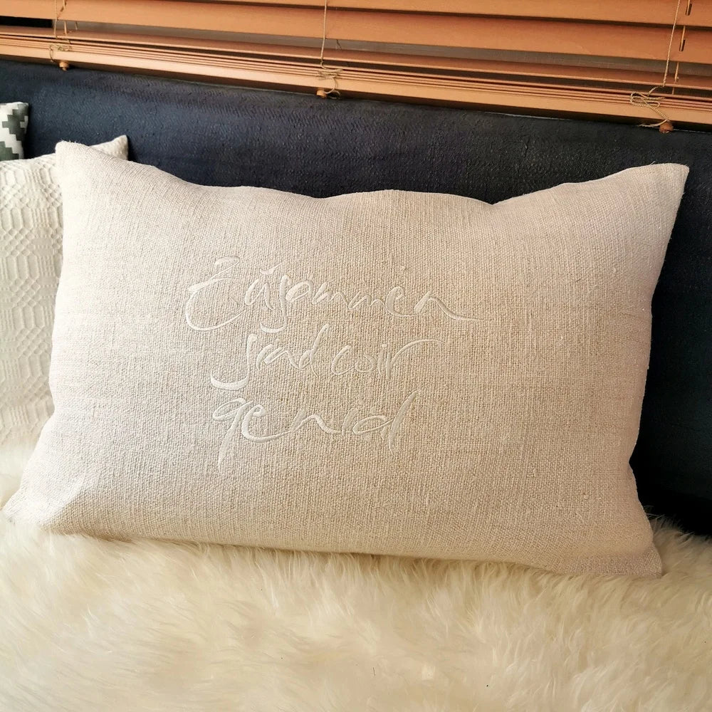 Naturfarbene Kissenhülle „Zusammen sind wir genial“ aus handgewebtem Vintage-Bauernleinen, 60x40 cm, dekoriert auf einem hellen Sofa