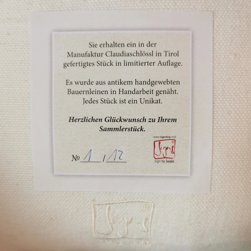 Detailansicht der Stickerei „Mein Herz geht auf“ (Sign by Jwala®) in Creme auf naturfarbener Bauernleinen-Kissenhülle, hochwertige Handarbeit im Nahaufnahme-Fokus
