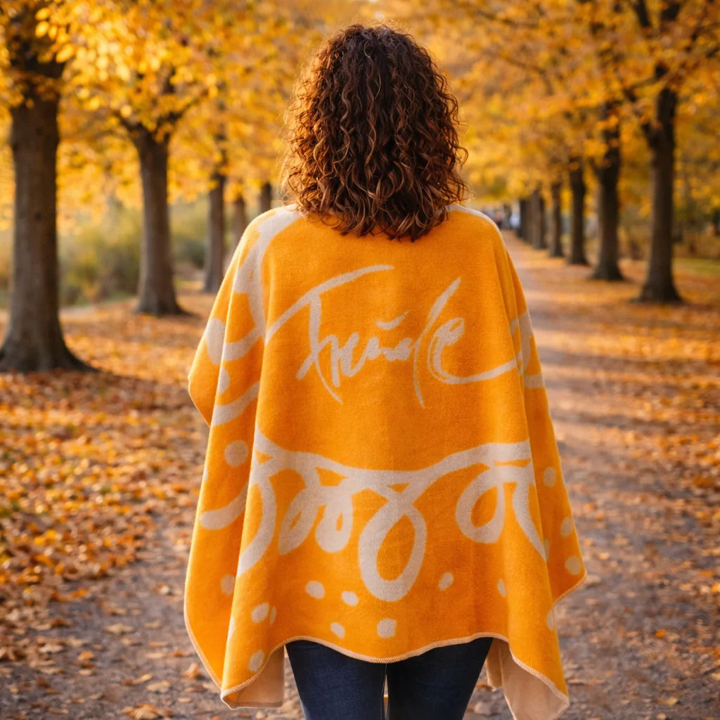 Frau auf einer Alle von hinten im Herbst - Poncho-Decke „Freude“: Geborgenheit, Leichtigkeit und positive Energie vereint – mit inspirierendem Sign by Jwala, weicher Flanellqualität und nachhaltiger Handwerkskunst aus Österreich.