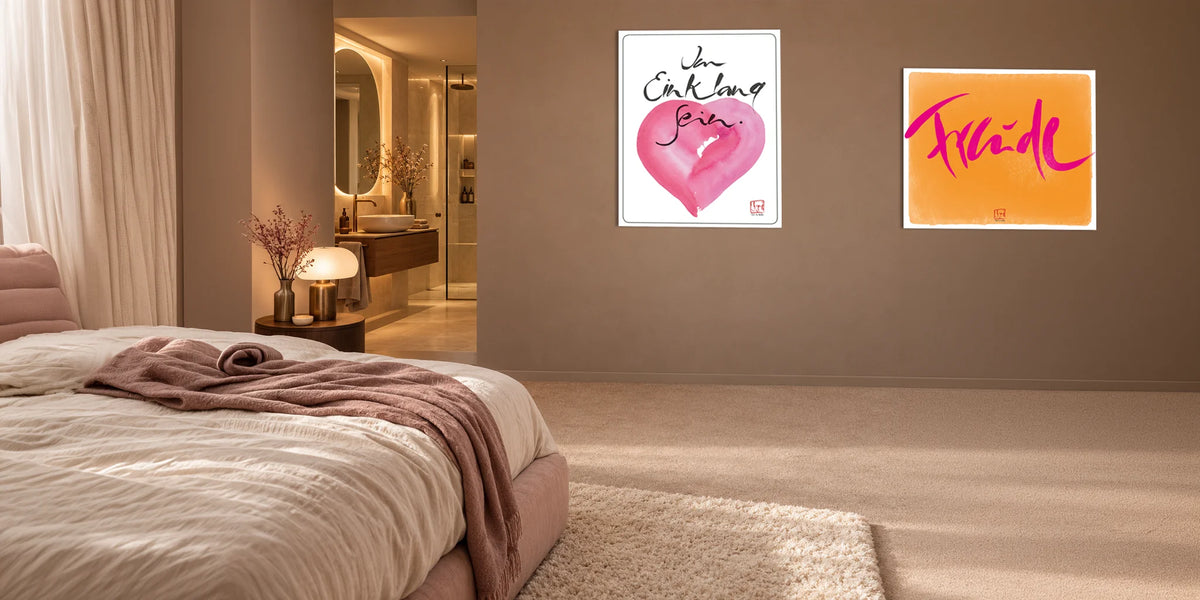 Gemütliche Schlafzimmer-Inspiration mit minimalistischer Dekoration und zwei gerahmten Kunstdrucken in Rosa und Orange an einer beigen Wand