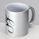 Detailansicht einer silbernen Metallic-Tasse mit dem schwarzen, geschwungenen Schriftzug Sign by Jwala® "Joy" an der Seite.