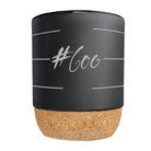 Schwarze Keramiktasse mit Korkboden ohne Henkel, bedruckt mit dem weißen Sign „#600“.