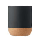Matte schwarze Keramiktasse in minimalistischer Rückansicht mit braunem Korkboden ohne sichtbaren Henkel oder Text.