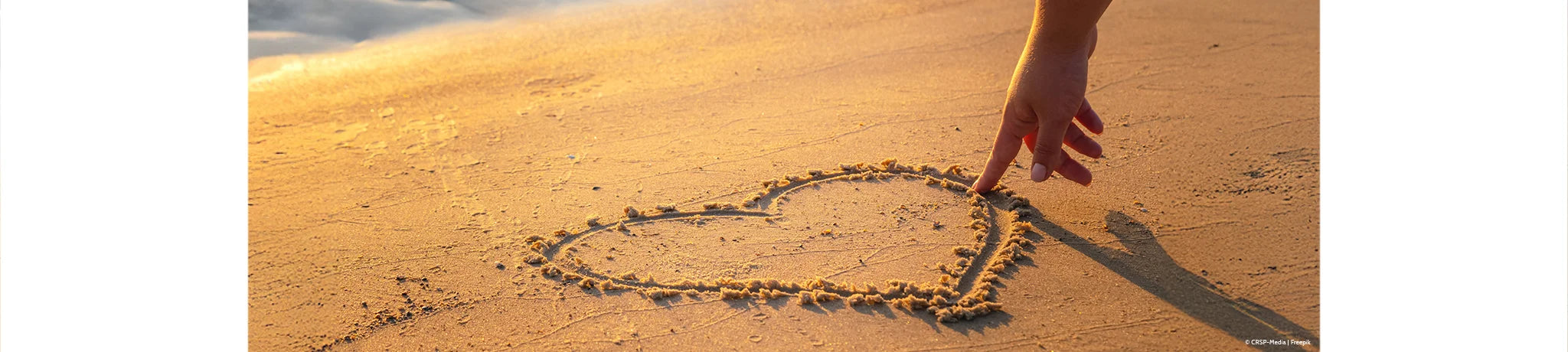 Frau, die ein Herz in den Sand zeichnet – aus dem Onlineshop SignShop Tirol