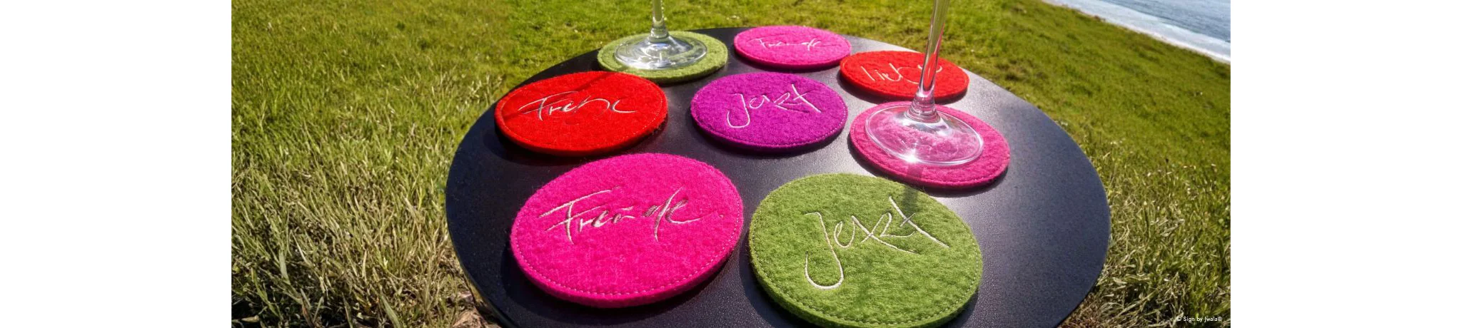 Bunte Glasuntersetzer mit inspirierender Botschaften in Rot, Grün und Rosa aus dem Onlineshop SignShop Tirol – farbenfrohe Akzente für den Tisch.