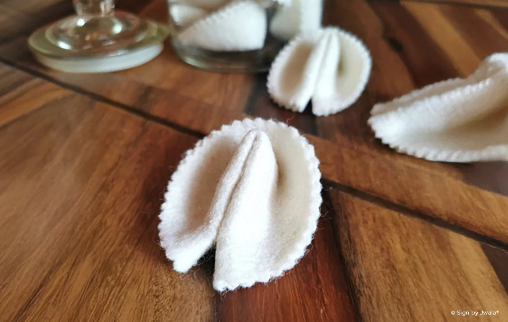 Das Bild zeigt handgemachte Glückskekse aus dem SignShop Tirol, die jeweils einen kleinen Zettel mit einer inspirierenden Botschaft oder einem Spruch enthalten. Die Glückskekse sind liebevoll arrangiert und laden dazu ein, Freude und positive Gedanken zu verschenken.