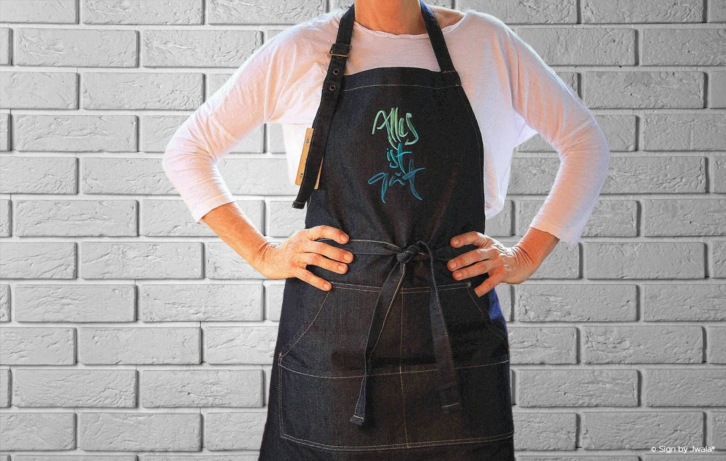 Schürze mit der Botschaft „Alles ist gut“ aus dem Onlineshop SignShop Tirol – handgemacht, inspirierende Küchenkleidung, liebevoll gestaltet, positive Affirmation.