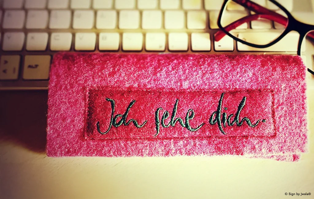 Rosa Brillentasche aus dem SignShop Tirol, liebevoll bestickt mit der Botschaft „Ich sehe dich“.