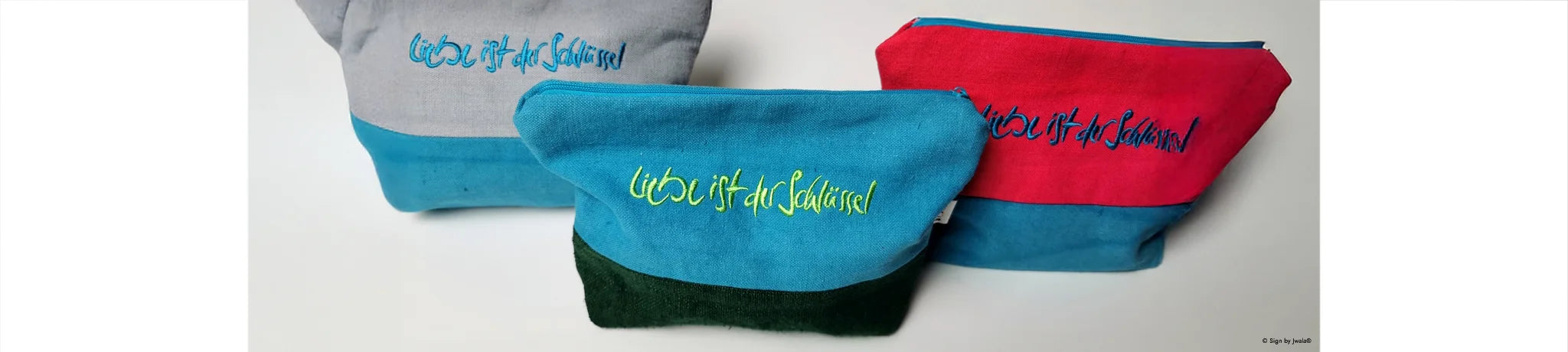 Hochwertige, bunte Kosmetikbeutel aus Bauernleinen mit der liebevollen Botschaft „Liebe ist der Schlüssel“, handgefertigt im SignShop Tirol.