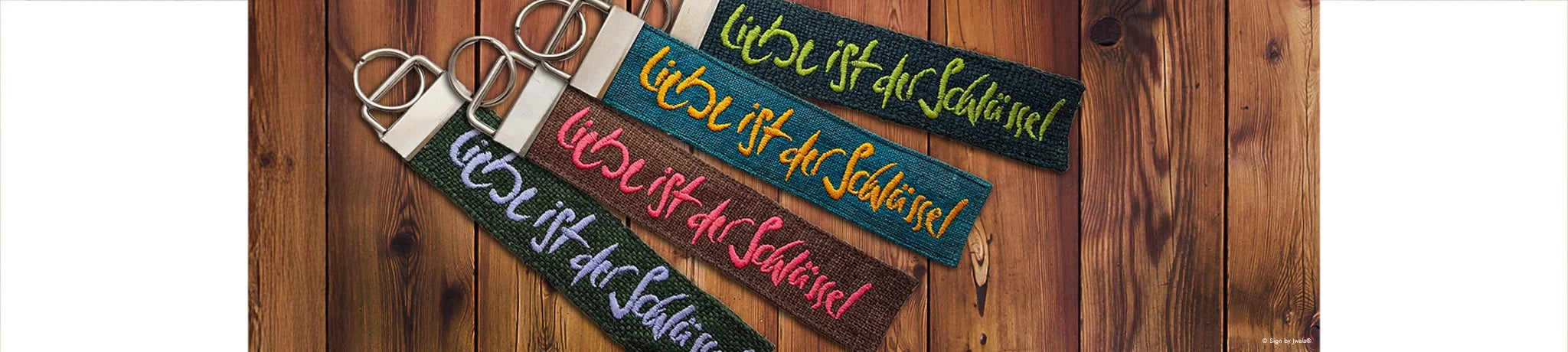 Verschiedene handgemachte Schlüsselanhänger aus Bauernleinen mit der Botschaft „Liebe ist der Schlüssel“, liebevoll gefertigt und im Onlineshop SignShop Tirol erhältlich.