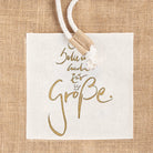Nahaufnahme der weißen Baumwolltasche auf dem Jute-Seesack mit dem goldenen Sign Ich bekenne mich zur Größe