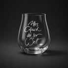 Ein edles Riedel-Glas aus Tirol mit der weißen geschwungenen Gravur „Alles Glück dieser Welt“ vor einem minimalistischen, dunkelgrauen Hintergrund.