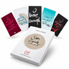 Das weiße Buch „SignGuide to the 54 SignCards“ von Jwala Gamper flach liegend mit fünf aufgefächerten, farbigen Motivationskarten im Hintergrund, darunter „I have enough“.