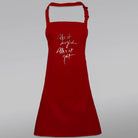 Rote Latzschürze bedruckt mit dem Jwala® Sign „Alles ist möglich. Alles ist gut.“ in silberner Schrift – exklusiv gestaltet von SignShop.tirol.