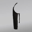 Schwarze Latzschürze in der Seitenansicht vor grauem Hintergrund – perfekt zum Personalisieren mit einer Jwala® Botschaft bei SignShop.tirol.