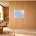 Modernes Kunstposter hinter Acrylglas im Querformat mit dem zartrosa Sign by Jwala 120x100 cm  „Stille“ auf hellblauem Hintergrund, als stilvoller Akzent an einer hellen Holzwand neben einem Loungesessel.