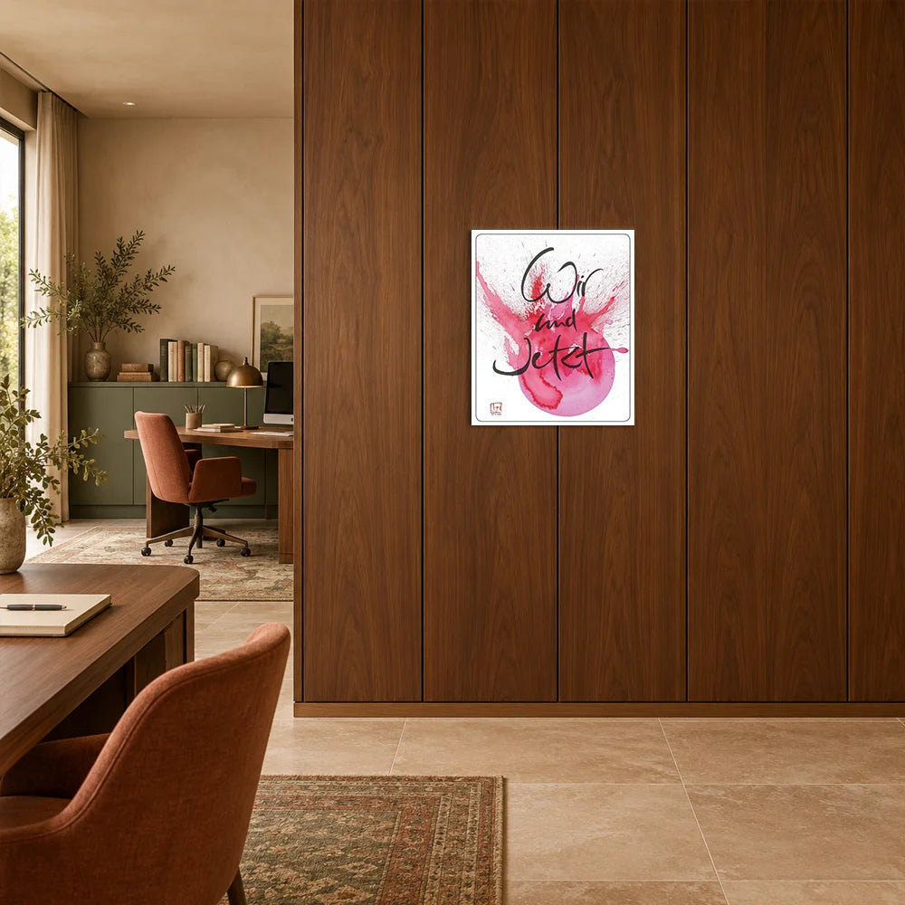 Modernes Wandbild auf gebürstetem Alu-Dibond mit dem Schriftzug Sign by Jwala®️ „Wir und Jetzt“ über einem magentafarbenen Aquarellkreis an einer dunklen Holzwand im Büro.