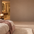 Detailansicht einer großen, leeren Wand in warmen Beigetönen innerhalb eines eleganten Schlafzimmers mit angrenzendem Badezimmer – ideal als Mockup-Hintergrund für die Präsentation von gemütlichen Wandbildern und Postern.