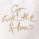 Detailansicht des goldenen Digitaltransferdrucks auf weißem Canvas-Stoff mit der inspirierenden Botschaft „Go with the flow“ in geschwungener Handschrift.
